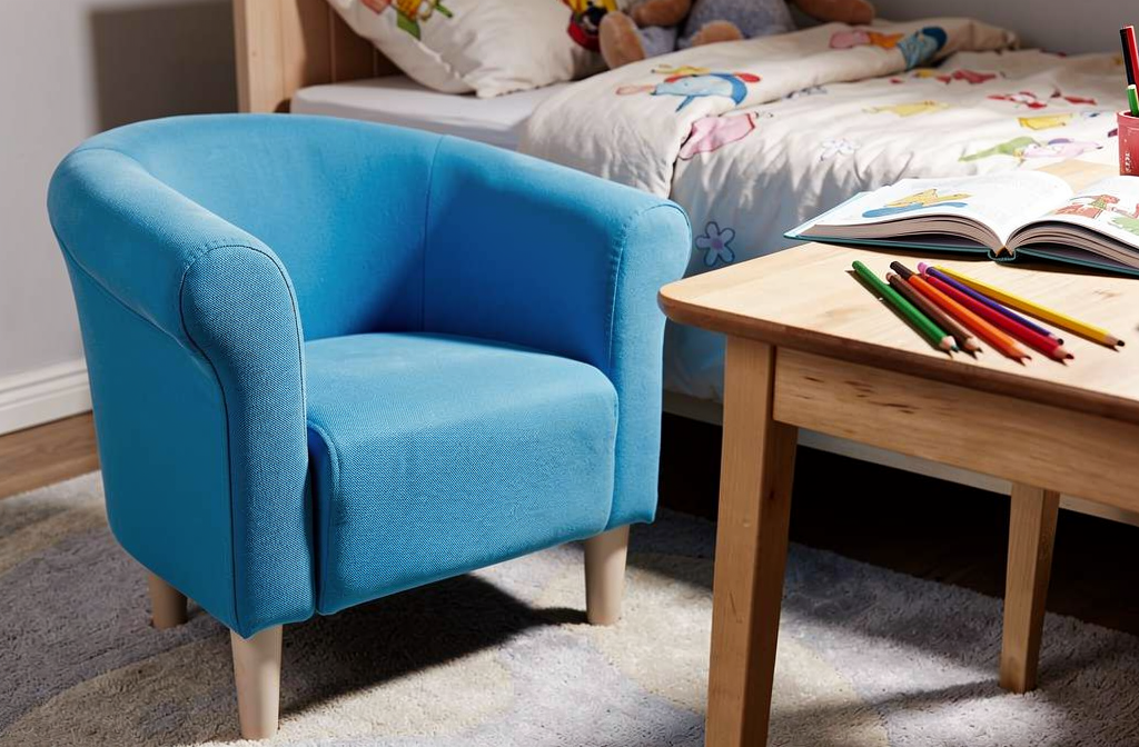 Niebieski fotel dziecięcy przy małym drewnianym biurku w pokoju dziecięcym.