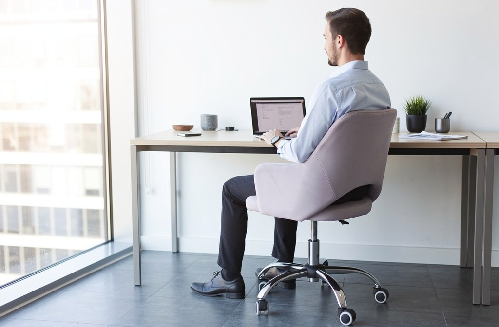 Ergonomiczne krzesło biurowe przy nowoczesnym biurku, przedstawiające prawidłową pozycję siedzącą w środowisku pracy.