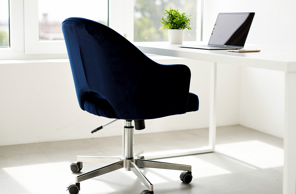 Granatowe welurowe krzesło obrotowe przy białym biurku w nowoczesnym domowym gabinecie
