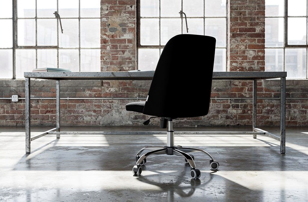 Czarne krzesło biurowe przy industrialnym biurku w loftowym wnętrzu z ceglaną ścianą